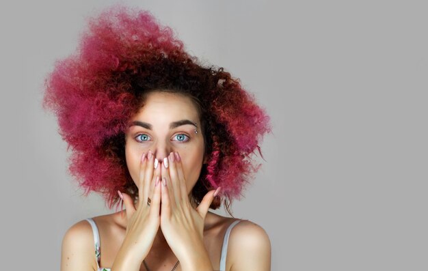 A girl of European appearance a Ukrainian with blue eyes and pink hair covered her mouth with her hands portrait