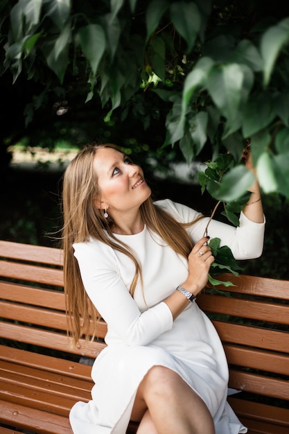 Ragazza europea guarda, tra le foglie di un cespuglio o di un albero