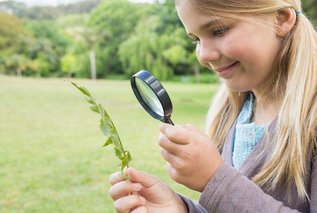 Girl examining leaves with magnifying glass at park