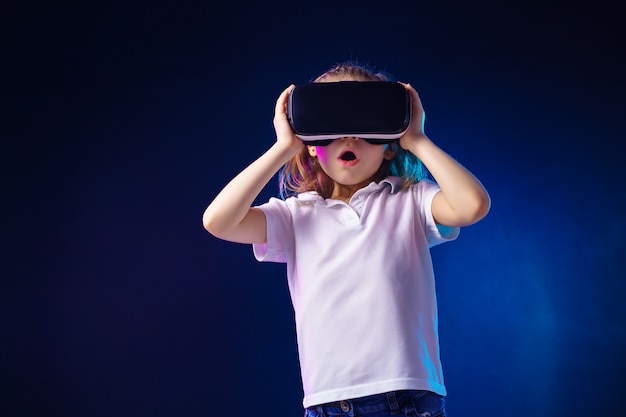 Девушка испытывает игру VR гарнитуры. Удивлены эмоции на ее лице. Ребенок использует игровой гаджет для виртуальной реальности.