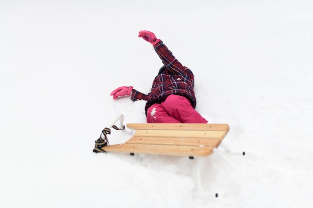 Photo girl falling down from sledge in winter park