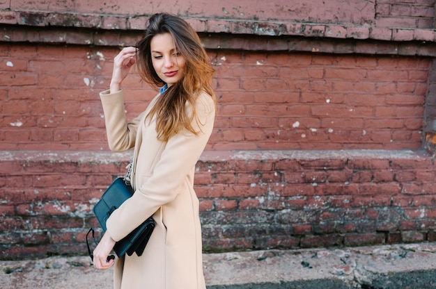 Girl in a fashionable coat walking on the summer city