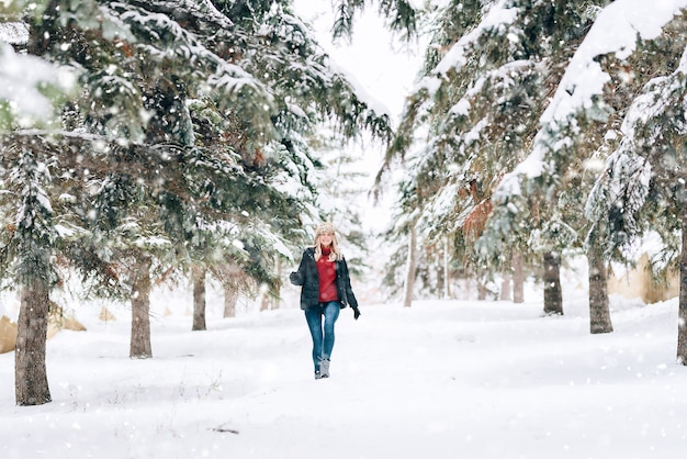 Девушка в модной зимней шапке с леопардовым принтом радуется на снегу