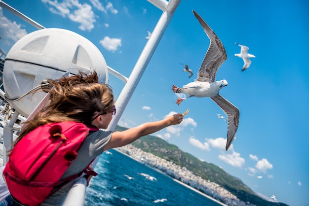 Girl feeding seagulls on the ferry boat