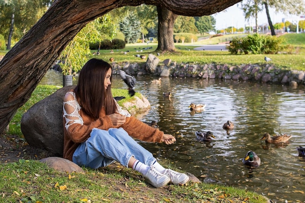 A girl feeds ducks on the shore of a pond