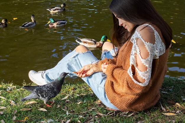 A girl feeds ducks on the shore of a pond