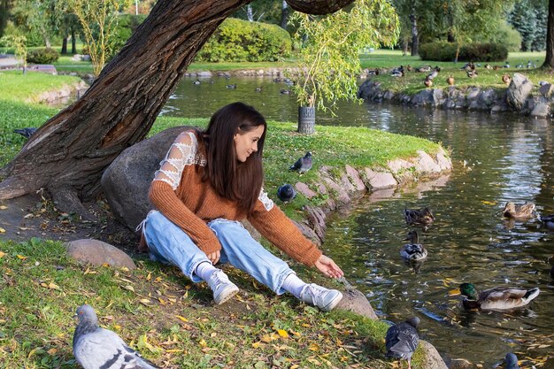 A girl feeds ducks on the shore of a pond