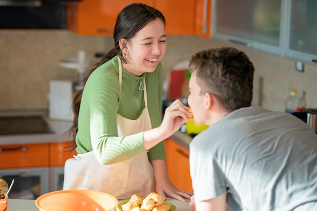 Girl feeds the guy with freshly baked eclairs.