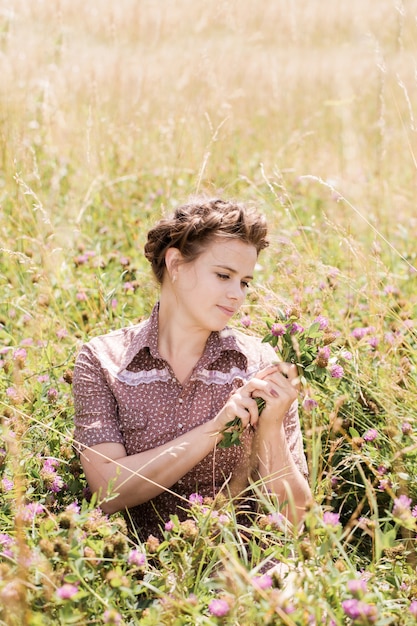 The girl in the field collects a bouquet of clover