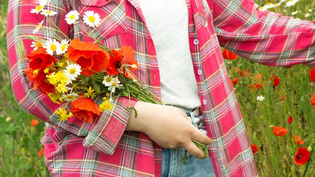 A girl in the field collects a bouquet of wild flowers