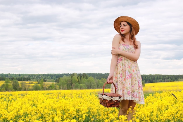 Girl in a field of flowers with basket and a hat