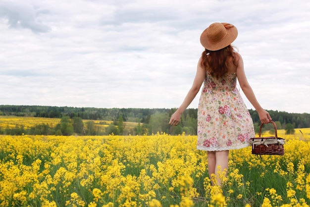 Girl in a field of flowers with basket and a hat