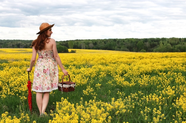 Girl in a field of flowers with an umbrella and a hat