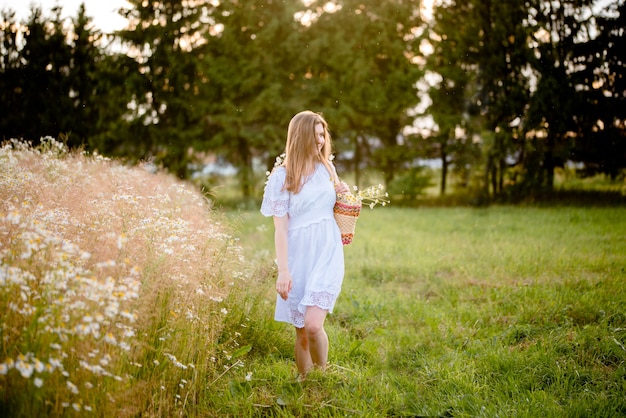 Girl in a field in the setting sun with daisies