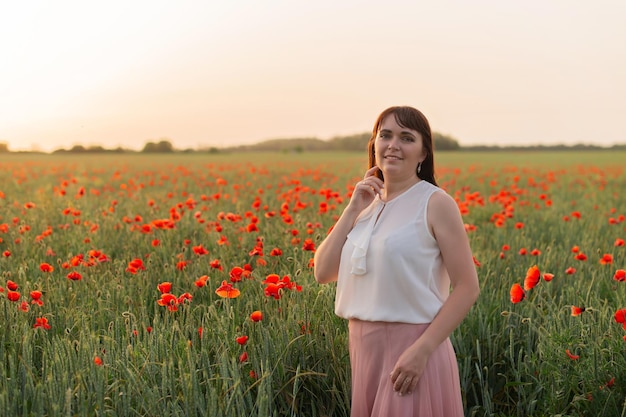 Photo a girl in a field with blooming poppies at sunset summer time