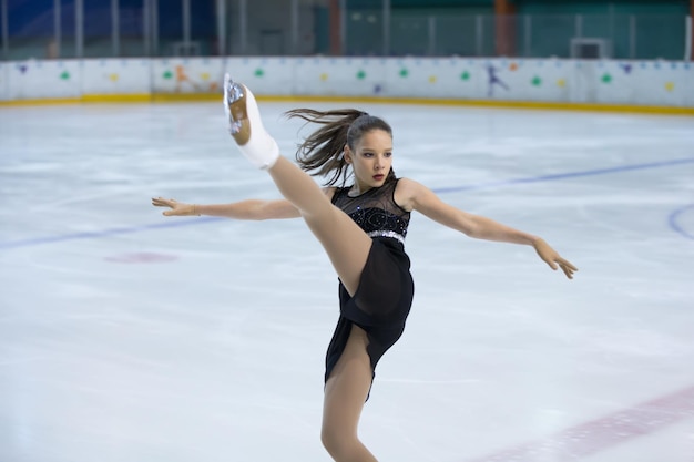 The girl figure skater performs a complex element