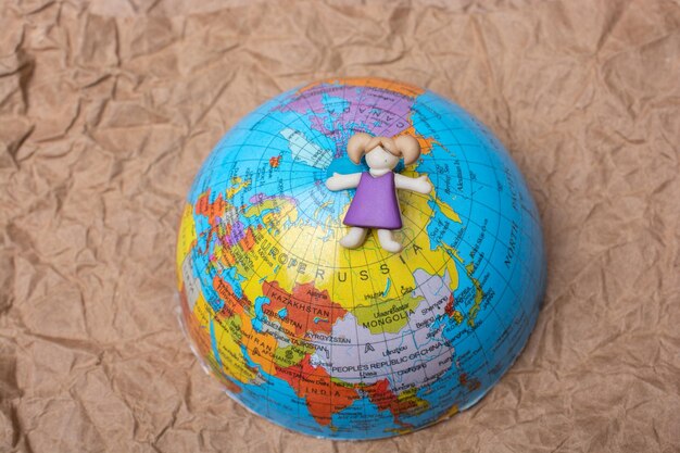 Girl figurine on top of globe as education and business concept