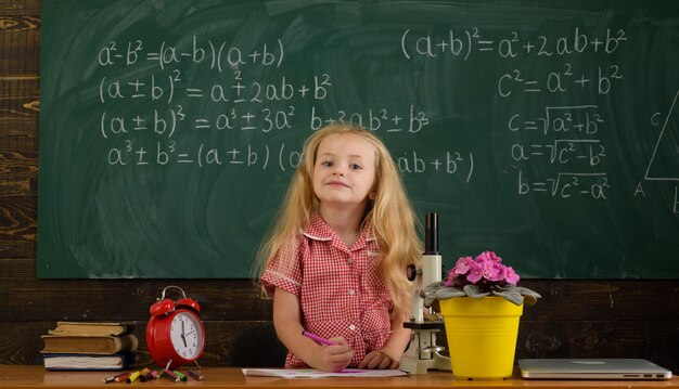 Photo girl first grader sitting at desk on first lesson on september 1 primary school child on september 1 or knowledge day