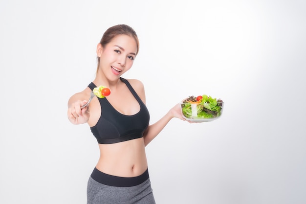 Girl in a fitness suite holds a salad bowl.