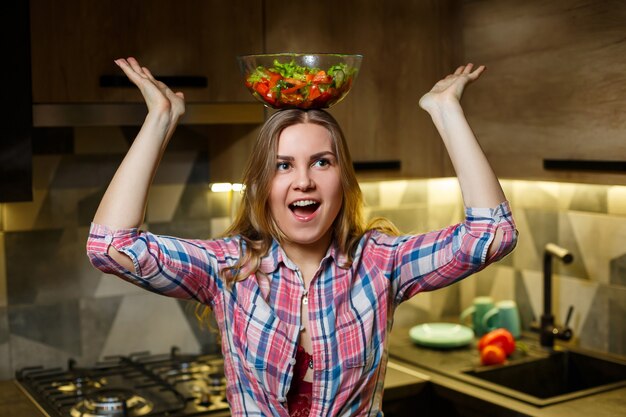 Girl fitness trainer vegetarian nutritionist prepare fresh vegetable salad in the kitchen. Watching her figure