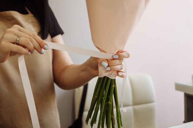 ハサミを使用して女の子の花屋はフラワーショップでチューリップの花束を飾る