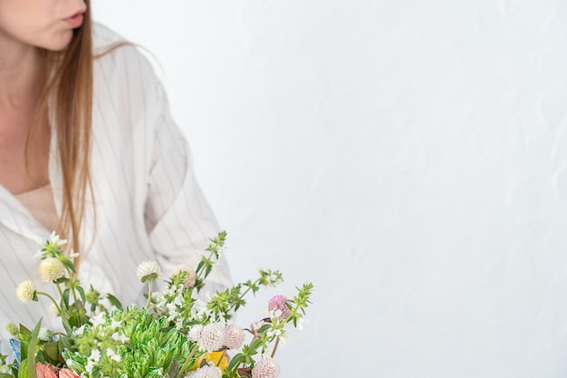 A girl florist with long hair presents a bouquet of chrysanthemums