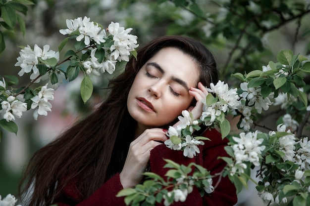 Girl in a flowery garden in a maroon coat