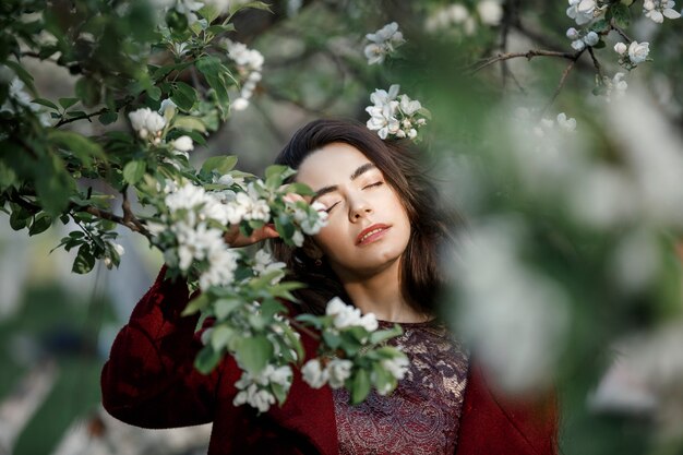 Girl in a flowery garden in a maroon coat