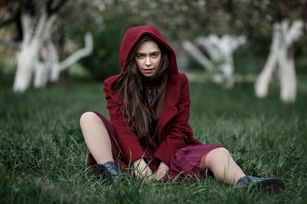 Girl in a flowery garden in a maroon coat