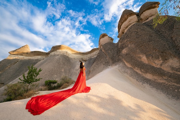 A girl in a flying dress with a long train on the background of balloons in Cappadocia