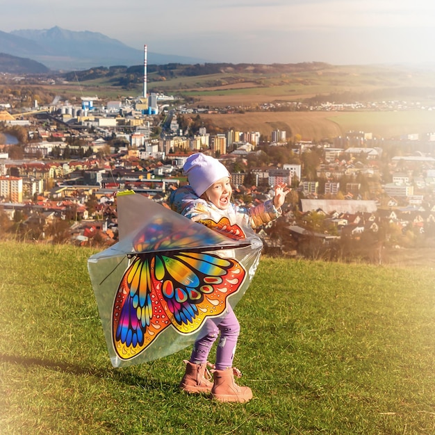 Girl flying a kite in a field over town