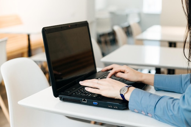 Girl freelancer in blue shirt working on laptop