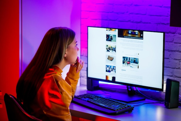 Girl freelancer looks on the computer screen news about forest\
fires and the virus covid19