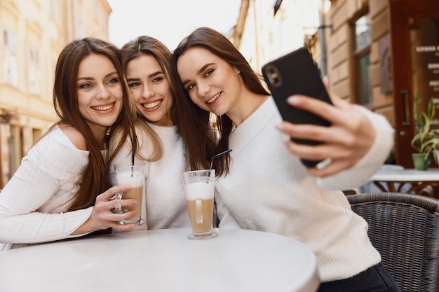 Girl friends taking a selfie at a cafe table