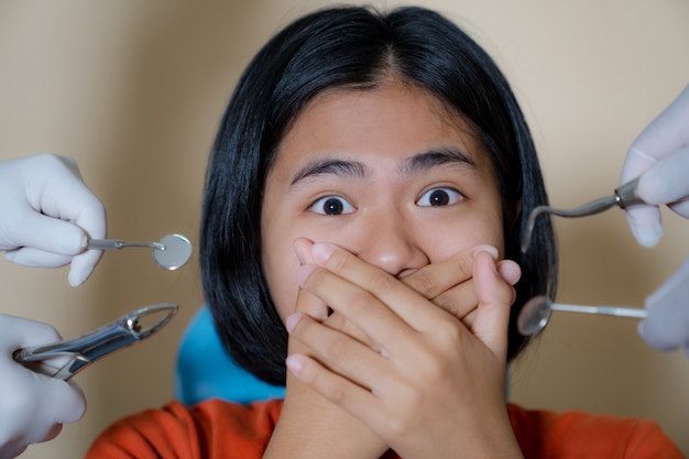 La ragazza spaventata dai dentisti copre la bocca nell'ufficio del dentista