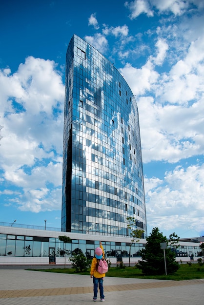 A girl in front of a large modern building against a blue sky Modern architecture City