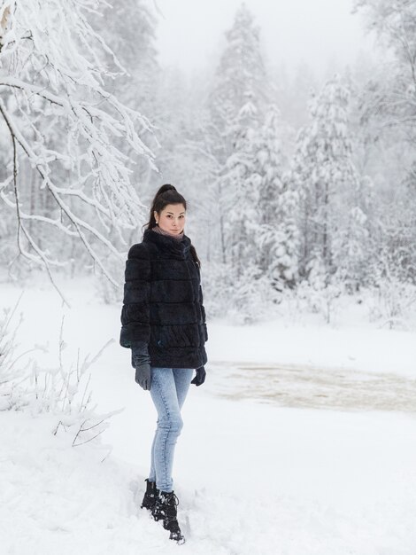 雪に覆われた森の毛皮のコートの女の子