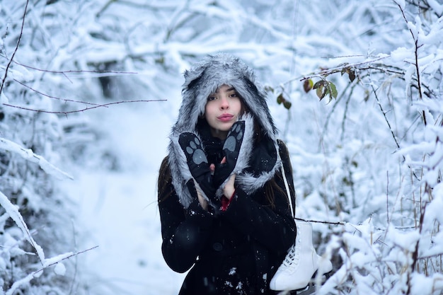 Girl in fur hat, mittens and coat with figure skates