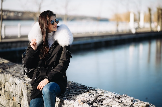 Girl in fur jacket outside by the lake