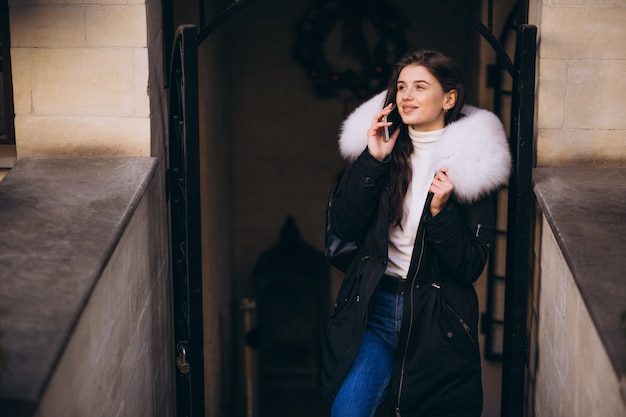 Girl in fur jacket talking on the phone outside