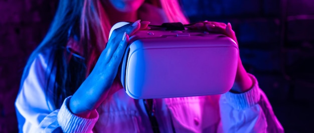 Girl gamer hold vr glasses goggles in futuristic purple neon light banner