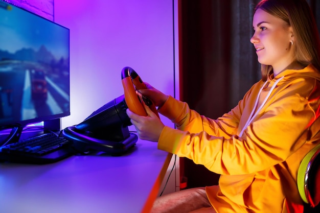 Girl gamer playing racing on a computer She uses a steering wheel emotional play