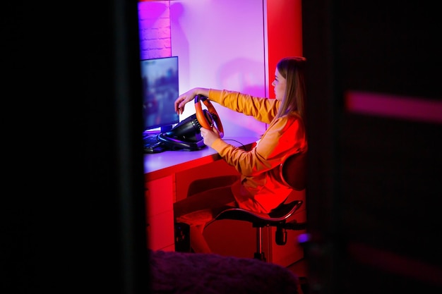 Girl gamer playing racing on a computer She uses a steering wheel emotional play