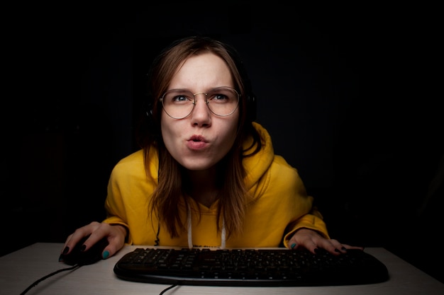 Girl gamer playing a video game on a computer at night at home, a student focused on the game