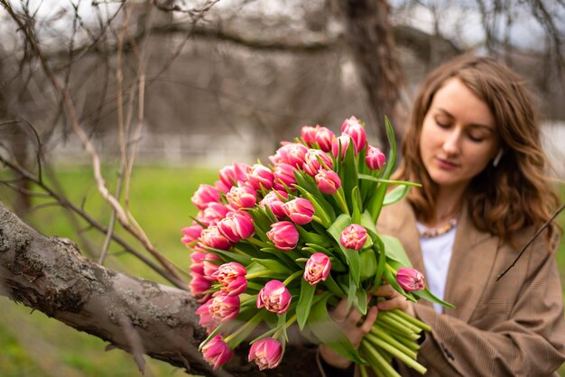 Girl in the garden with a large bouquet of pink tulips