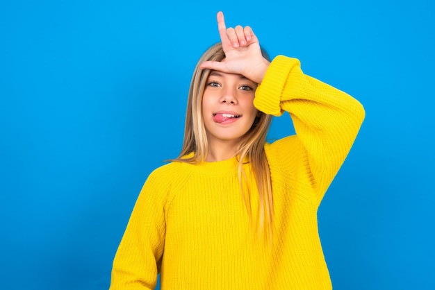 girl gestures with finger on forehead makes loser gesture makes fun of people shows tongue