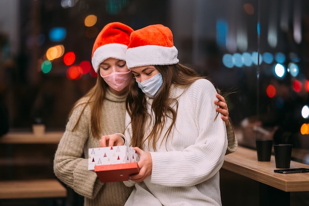 The girl gives a gift to her female friend in caffe