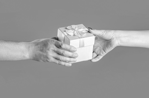 Girl gives a gift to man Woman hands holding gift Gift box in hand surprise and holiday concept Man hands holding valentines day gift Black and white