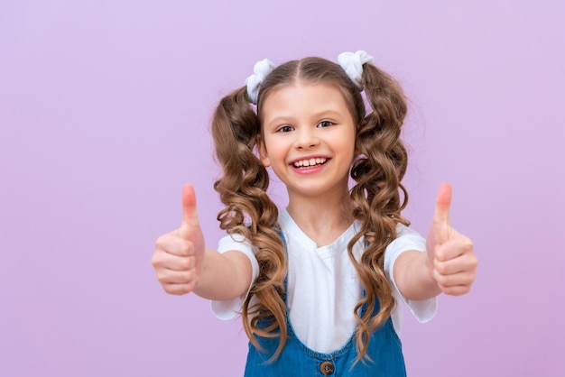 A girl gives a thumbs up, a child with curly long hair.