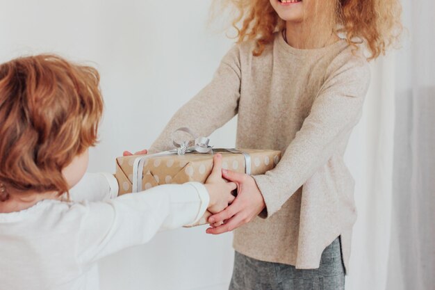 Girl giving gift box to brother at home